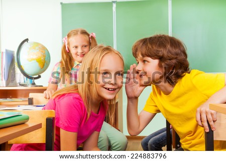 Small boy tells secret to other girl in school
