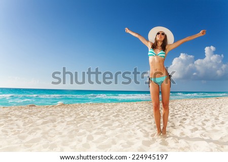 Beautiful attractive woman standing on the beach with lifted hands