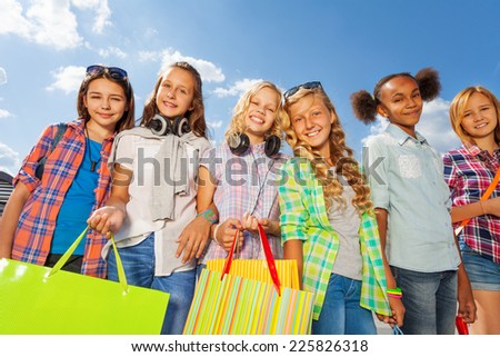 Girls with colorful shopping bags stand arm-in-arm