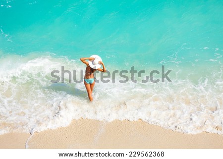 Young woman from back with white hat on the beach