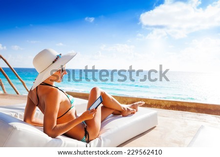 Young woman with hat laying and reading e-book