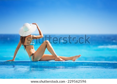 Girl from back with white hat in striped bikini