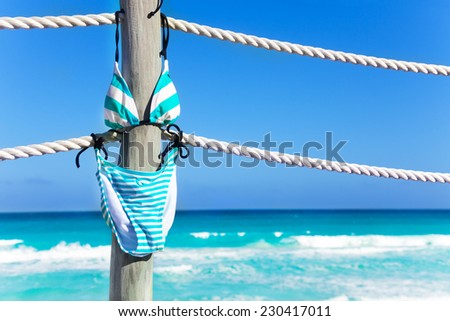 Swimming suit hanging on the white ropes of pier in summer vacation time with blue ocean on background