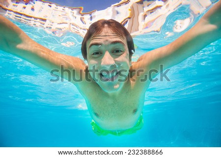 Close up view of smiling man swimming underwater