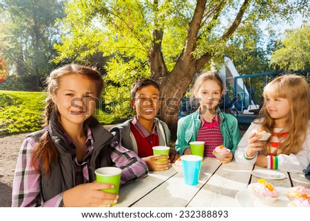 International children drink tea from cups outside