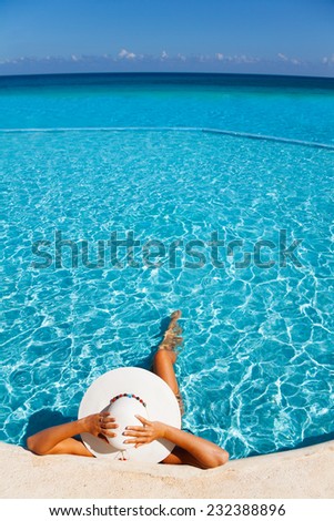 Woman holds white hat with hands laying in water