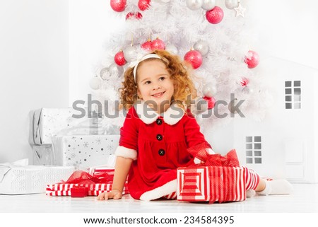 Little girl with presents under the Christmas tree
