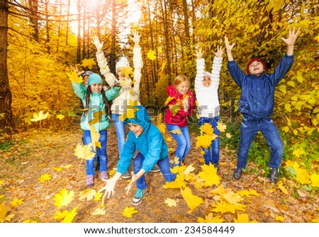 Happy children playing with flying leaves