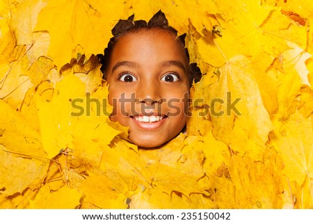 Face of a little African boy in autumn leaves