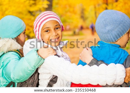 Happy children stand close with arms on shoulders