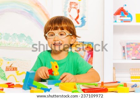 Smart boy with toy hammer in classroom