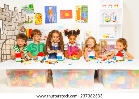 Little boys and girls constructing toy houses