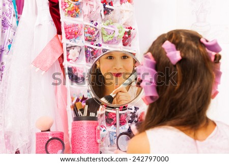 Smiling attractive girl making up face in mirror