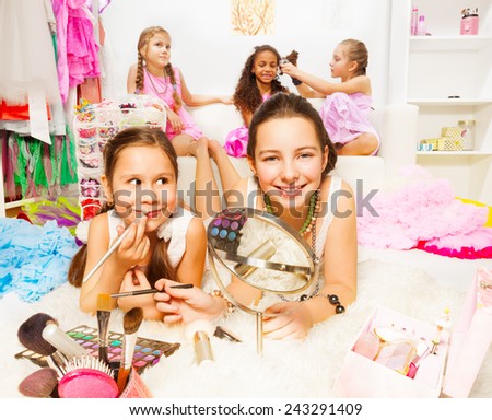 Pretty girls applying make-up with friends behind