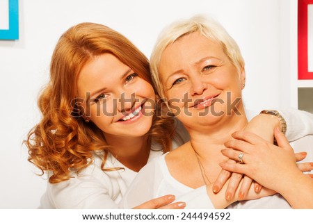 Smiling and hugging daughter with old mother
