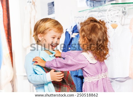 Happy boy with girl who fits on him vest in store