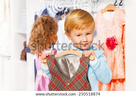 Boy with hanger and vest, girl choosing clothes