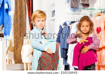 Boy holding vest and girl with sweater standing
