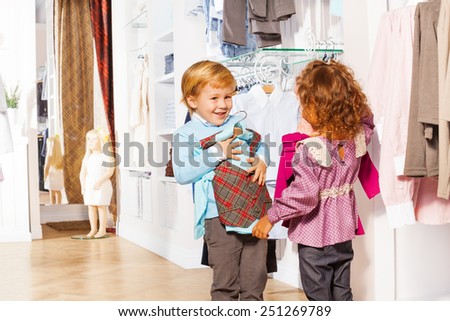 Smiling boy fitting vest and girl holding sweater