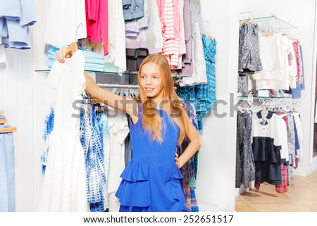 Blond girl with long hair holds dress on hanger