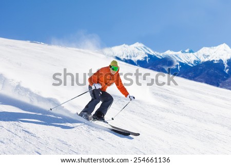 Young man in ski mask sliding fast while skiing
