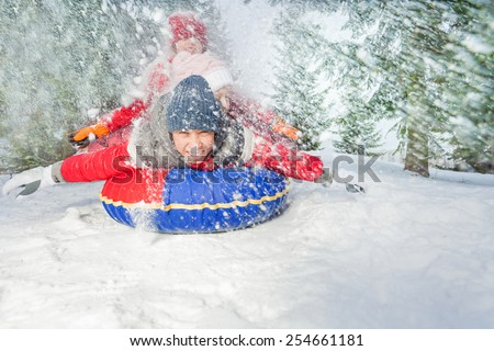 Happy friends on snow tube in winter during day