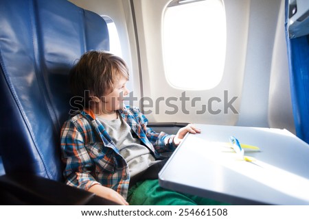 Happy boy sit in plane with toy model on table