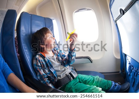 Cute boy with toy plane sit by the airplane window
