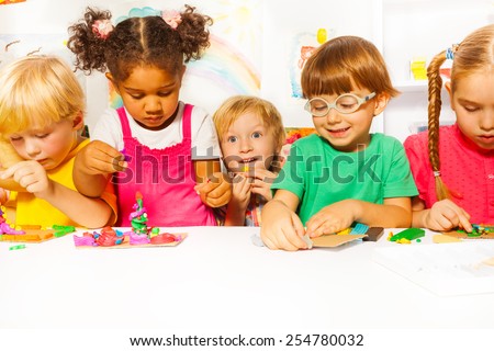 Group of kids in the kindergarten play with modeling clay in the class