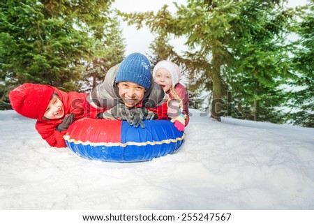 Excited girl and two boys on snow tube in winter