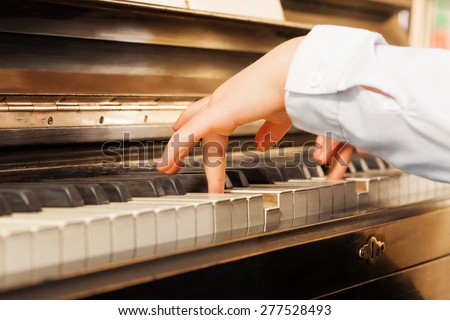 Close-up view of child\'s hands playing on piano