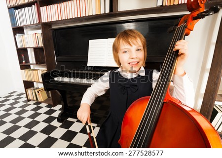 Happy kid in school dress playing on the cello