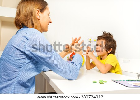 Boy exercises putting fingers with therapist