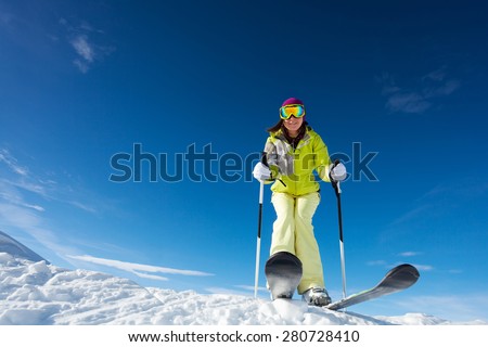 View from below of happy woman in mask  holding ski poles and ready to ski at Krasnaya polyana ski resort and Caucasus mountains in Sochi, Russia
