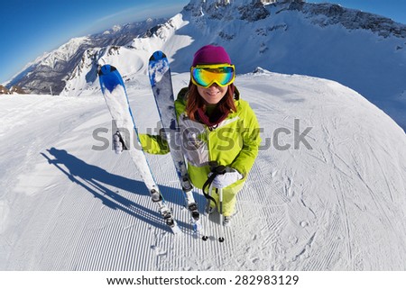 View of woman in mask standing and holding ski and ski poles during sunny winter day on Krasnaya polyana ski resort and Caucasus mountains in Sochi, Russia