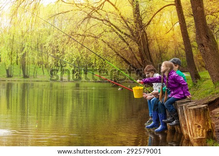 Happy kids fishing together near beautiful pond