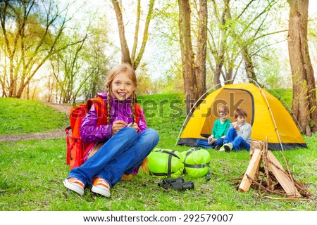 Happy children relax near the wooden bonfire, tent