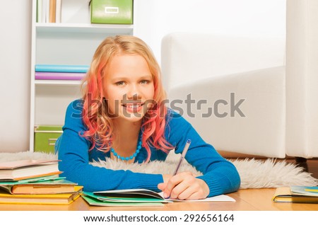 Nice beautiful blond girl with pink colored hair write in textbook at home bedroom