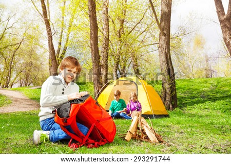 Boy packing the things into red rucksack in camp