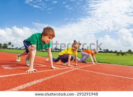 Kids in uniforms on bended knee ready to run
