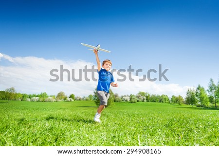 Happy boy holding airplane toy during running