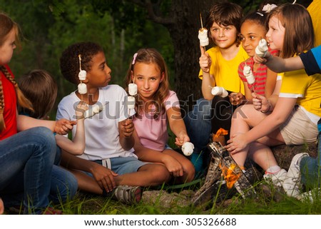 Group of children with s\'mores near bonfire