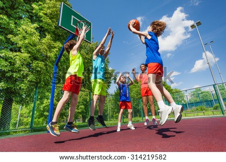 Teens jump for ball during basketball game