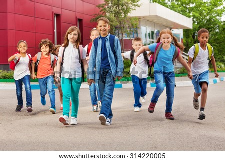 Children with rucksacks near school walking