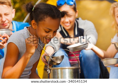 Close-up of African girl cooking soup at campsite