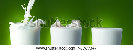 Filling the glass with milk with splashes on green
