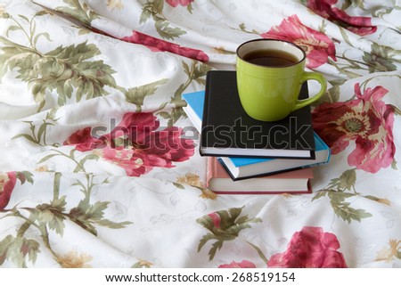 green cup of tea on a pile of books to read to learn bed bed linen training floral print
