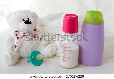 objects on a light background diapers bottle of breast milk, nipple, toy doll, a group of items of daily use to take care of the baby