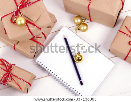 list of gifts for Christmas. Drawing up a list of gifts. presents in kraft paper vintage white wooden background. pencil, notebook