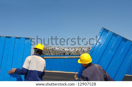 Two workers moving a fence